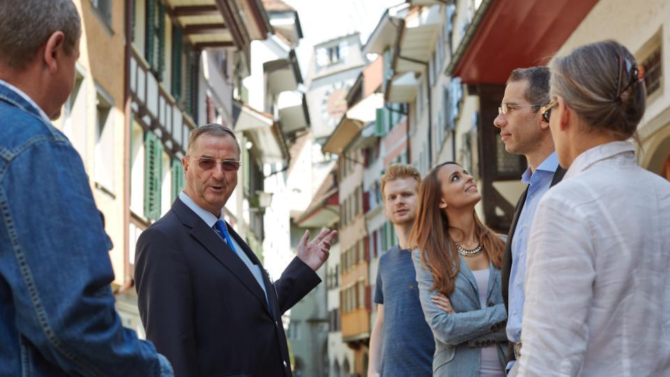 Ein Stadtführer erläutert die Geschichte von Zug in der Altstadt ein zwei Herren und drei Frauen.