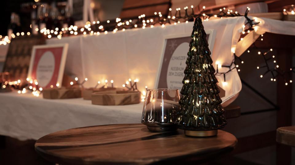 Kleine Holzskulpturen stehen auf einem weihnachtlich gedeckten Tisch.