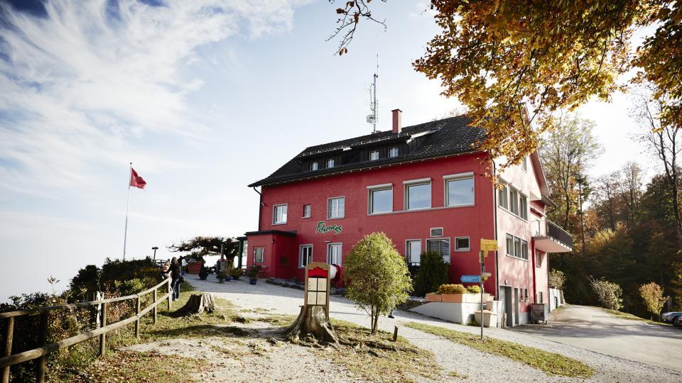 Das Restaurant mit der roten Fassade ist von herbstlichen Bäumen umgeben.