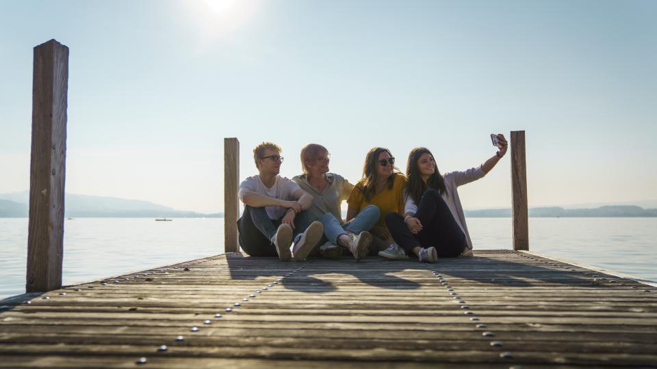 Gruppe junger Leute schiesst ein Selfie auf dem Steg am Zugersee