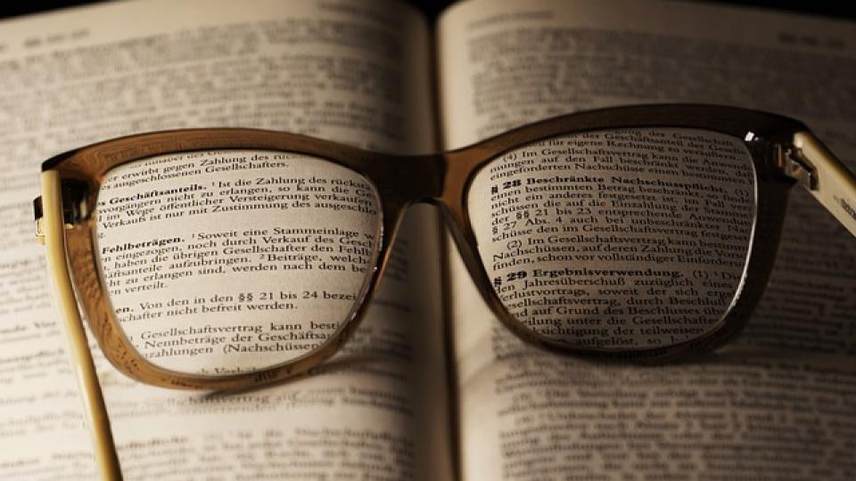 Eine Brille liegt auf einem aufgeschlagenen Buch.