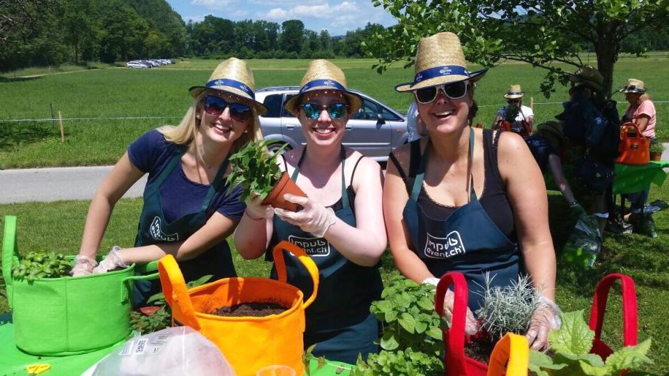 Drei Frauen lächeln in die Kamera, während sie ihren Garden Bag bepflanzen.