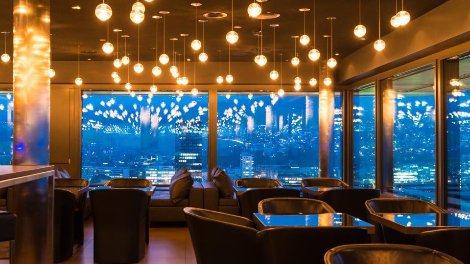 Lounge mit Ledersesseln und Fensterfront mit Blick über die Stadt Zug