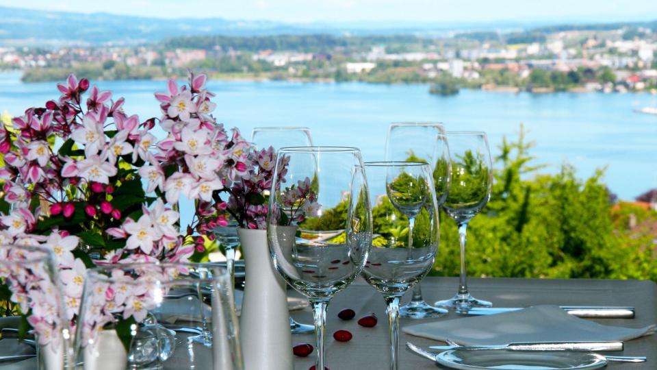 Gedeckter Tisch mit Blumen und im Hintergrund ist der Zugersee und Cham zu sehen.