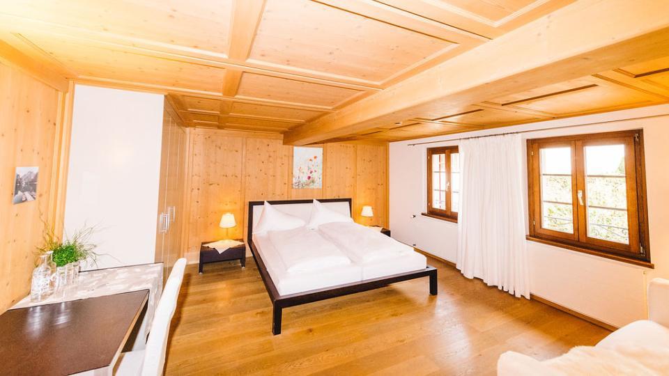 Doppelbett mit weisser Bettwäsche stehe auf einem hellen Holzboden.