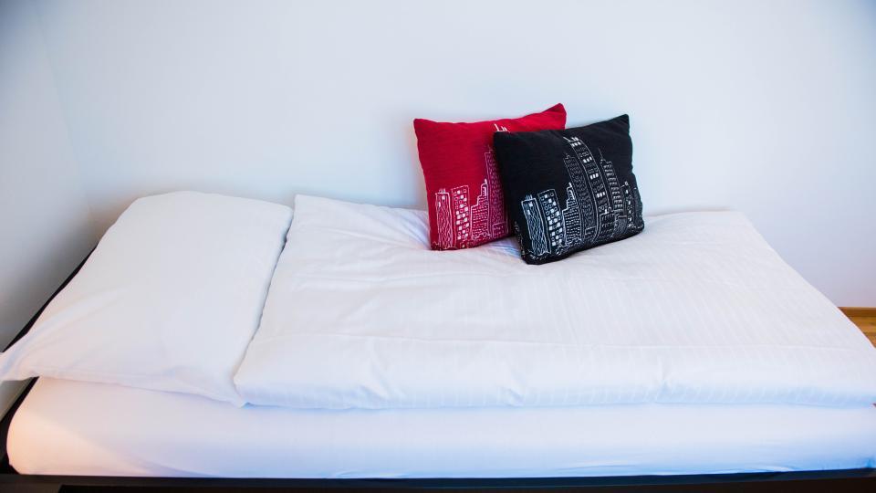 Bett mit zwei Kissen steht auf einem hellen Holzboden.