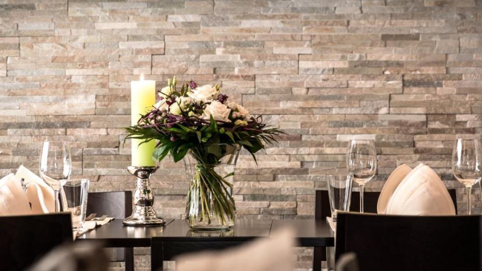 Dekorierter Tisch mit Blumen im Restaurant Ochsen vor einer Steinwand.
