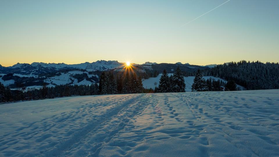 Sonnenuntergang mit Schneeschuhspuren im Schnee