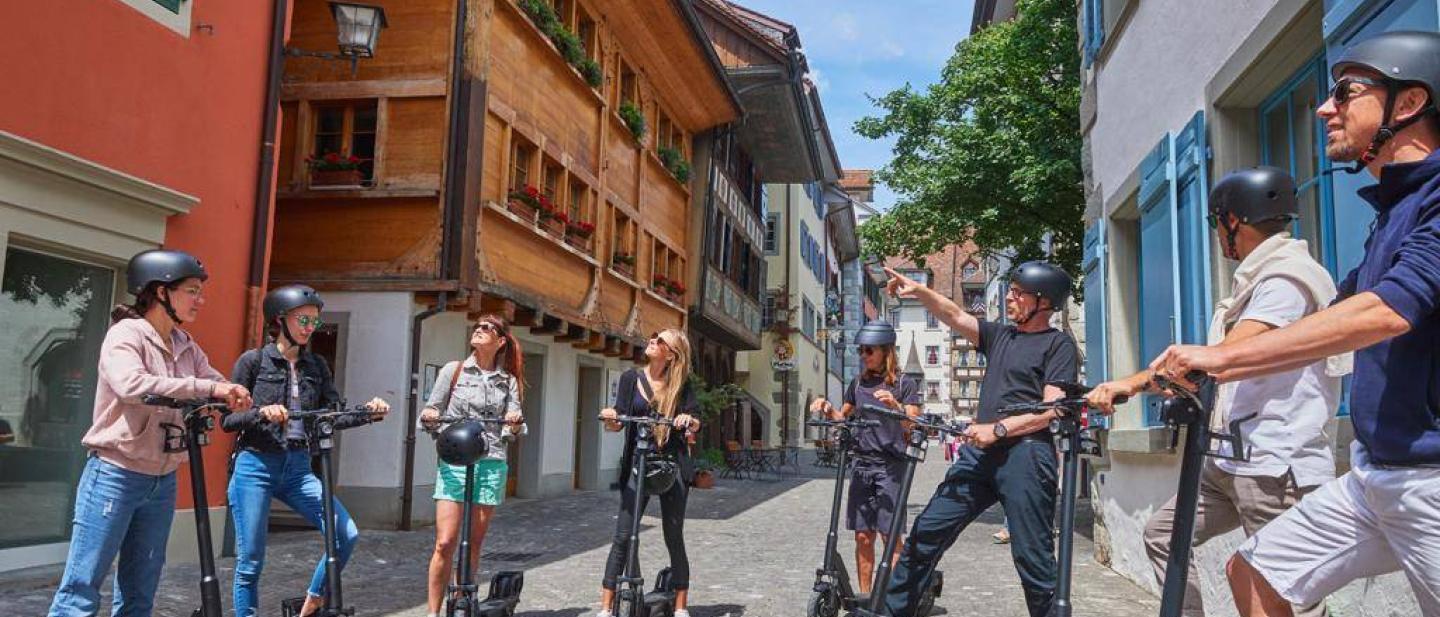 Eine Gruppe Menschen steht mit ihren E-Scootern in der Zuger Altstadt