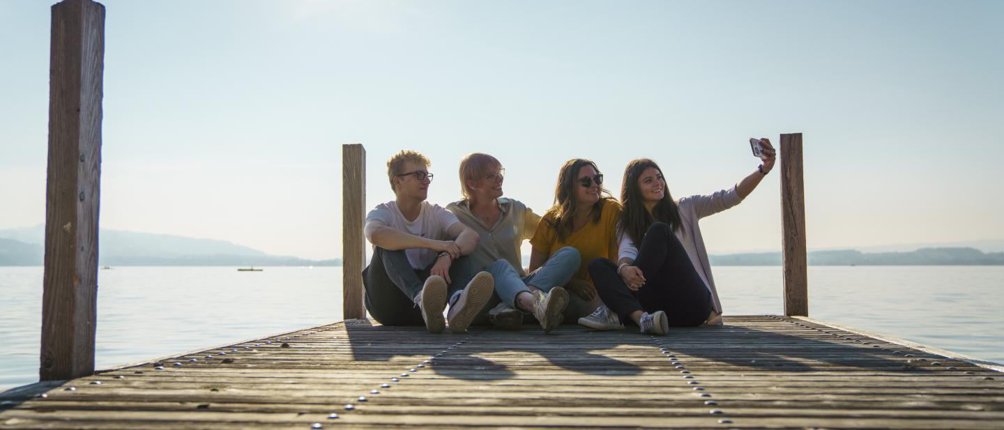 Gruppe junger Leute schiesst ein Selfie auf dem Steg am Zugersee
